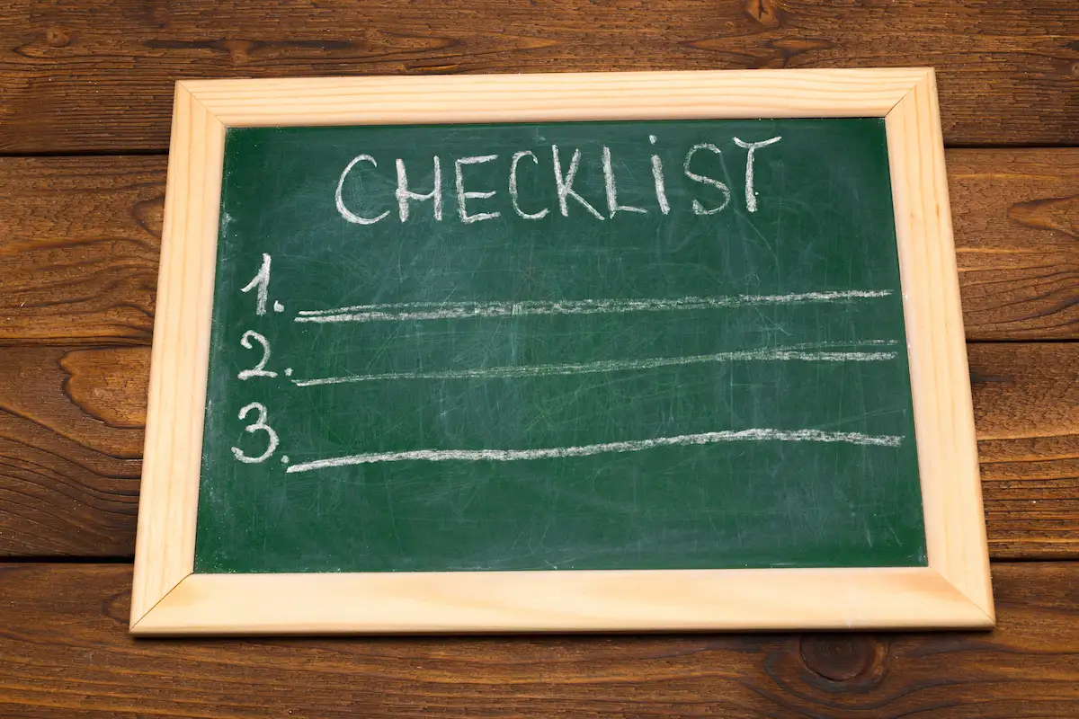 A detailed checklist on a clipboard or tablet, surrounded by household items, labeled boxes, and organized workspace.